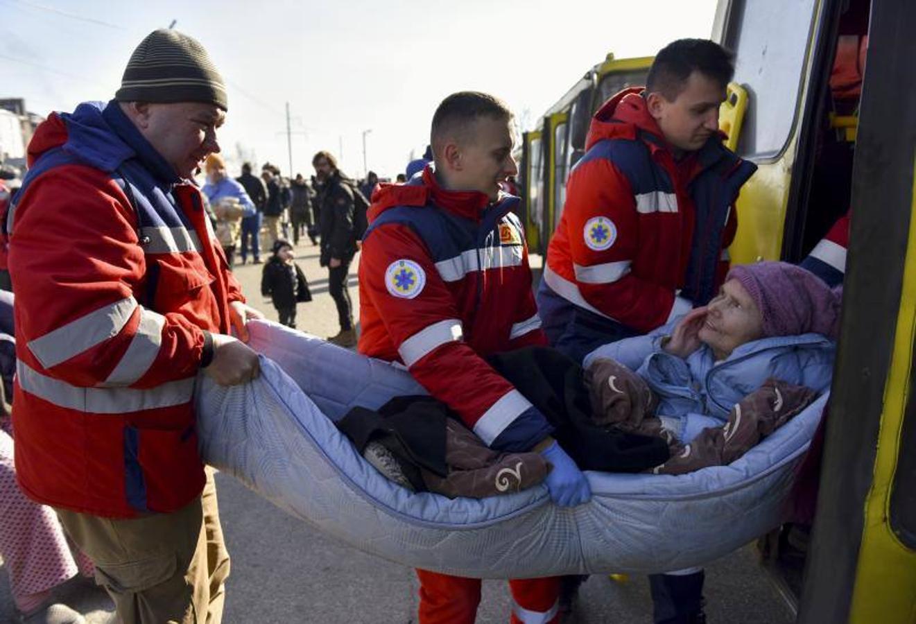 Los trabajadores médicos ayudan a una anciana después de que fue evacuada de un pueblo cercano a Kiev.