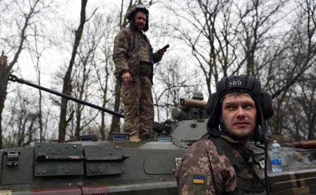 Dos soldados ucranianos, junto a un vehículo blindado, en la región de Járkov.