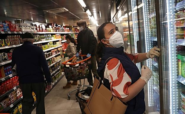 Una mujer compra en un supermercado con la mascarilla puesta 