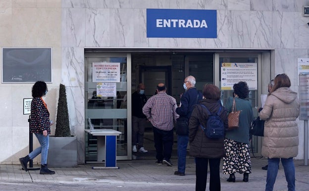 Imagen principal - Colas y carteles explicativos que remiten al ciudadano a los nuevos procedimientos. 