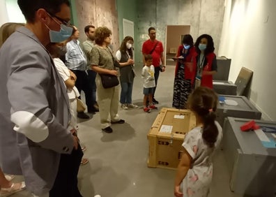 Imagen secundaria 1 - En la primera foto, los visitantes asisten a la colocación de unas piezas en la exposición. En la segunda , cajas en las se han transportado las obras al Museo Ruso y, en la última, un momento de la visita.