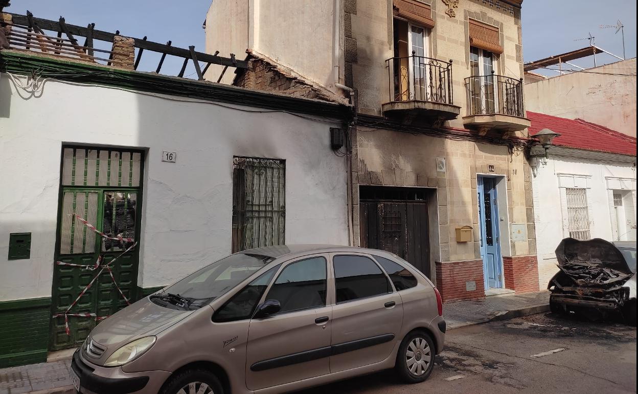 Estado en el que ha quedado la vivienda tras el incendio junto a la casa con la fachada afectada y el coche calcinado en el anterior fuego. 