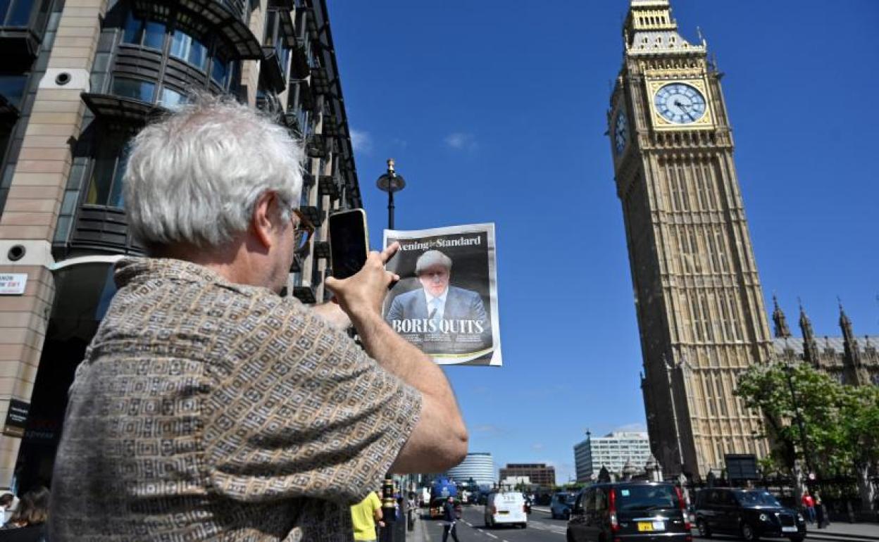 Un ciudadano fotografía una periódico con la dimisión de Johnson y el Big Ben al fondo. 