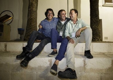 Imagen secundaria 1 - Una treintena de artistas posa el domingo por la noche tras la clausura del festival; Phil Plata, Josu Camacho y Juan de Castro, organizadores del Pueblos Blancos Music Festival, y Joe King Carrasco, con la guitarra en la cabeza en la plaza de Montejaque. 