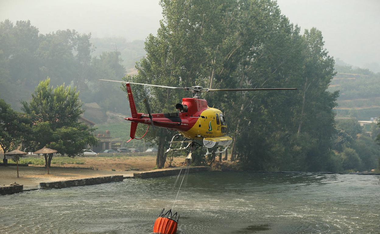 Un helicóptero carga agua en una piscina natural para sofocar un incendio provocado en el Valle del Jerte el pasado julio. 