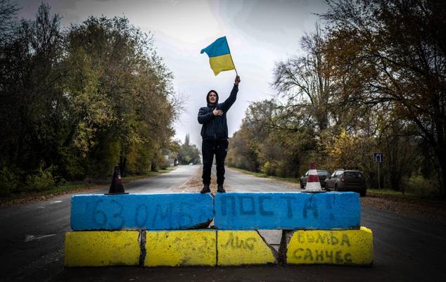 Un residente local ondea una bandera ucraniana en un antiguo puesto de control ruso a la entrada de Kherson mientras los residentes locales celebran la liberación de la ciudad, el 13 de noviembre de 2022.