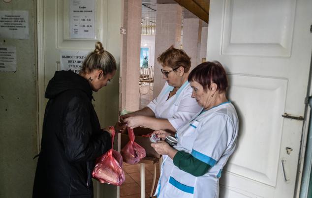 Una mujer evacuada de la región de Jersón hacia territorio bajo control ruso recibe su ración de comida después de llegar a un centro de alojamiento temporal en Dzhankoi, Crimea, 14 de noviembre de 2022.