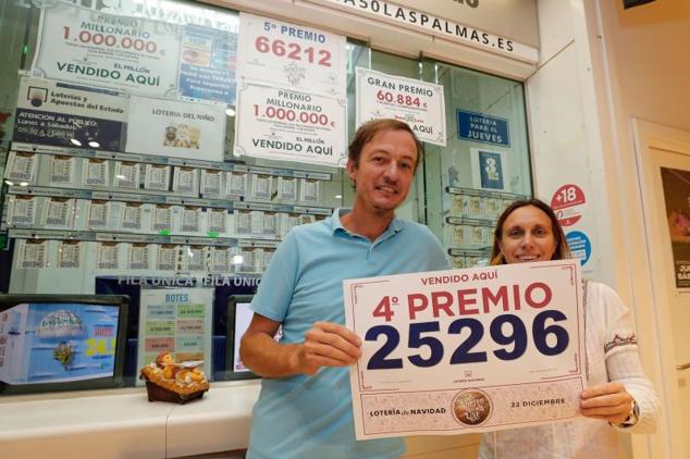 Los propietarios de la Administración de Loterías 50 de Las Palmas de Gran Canaria Manuel Izquierdo y Susana Alcántara muestran el cartel con el número 25.296
