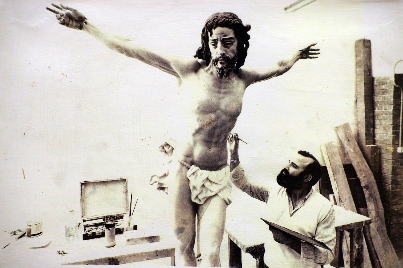 El Cristo del Perdón es obra del escultor Suso de Marcos, nacido en Boimorto (La Coruña), formado artísticamente en La Coruña y Madrid, pero afincado en Málaga, donde fue profesor de la Escuela de Artes de San Telmo. En la fotografía, se observa al artista ultimando la obra, que fue bendecida el 4 de abril de 1987, coincidiendo con el septenario que se le dedicaba a la Virgen de los Dolores.