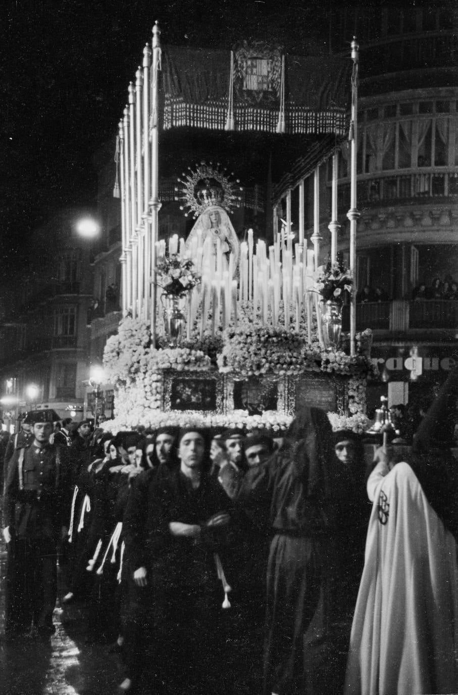 En esta instantánea de 1946, tomada en la calle Larios, aparece la actual Virgen de la Estrella con la antigua corona de procesión de la Virgen de la Paz, de la cofradía de la Sagrada Cena. Se trataba de la primera salida procesional de la Dolorosa, ya adquirida por la hermandad, después de que fuera retirada la talla anterior, cedida por José María Souvirón Rubio.