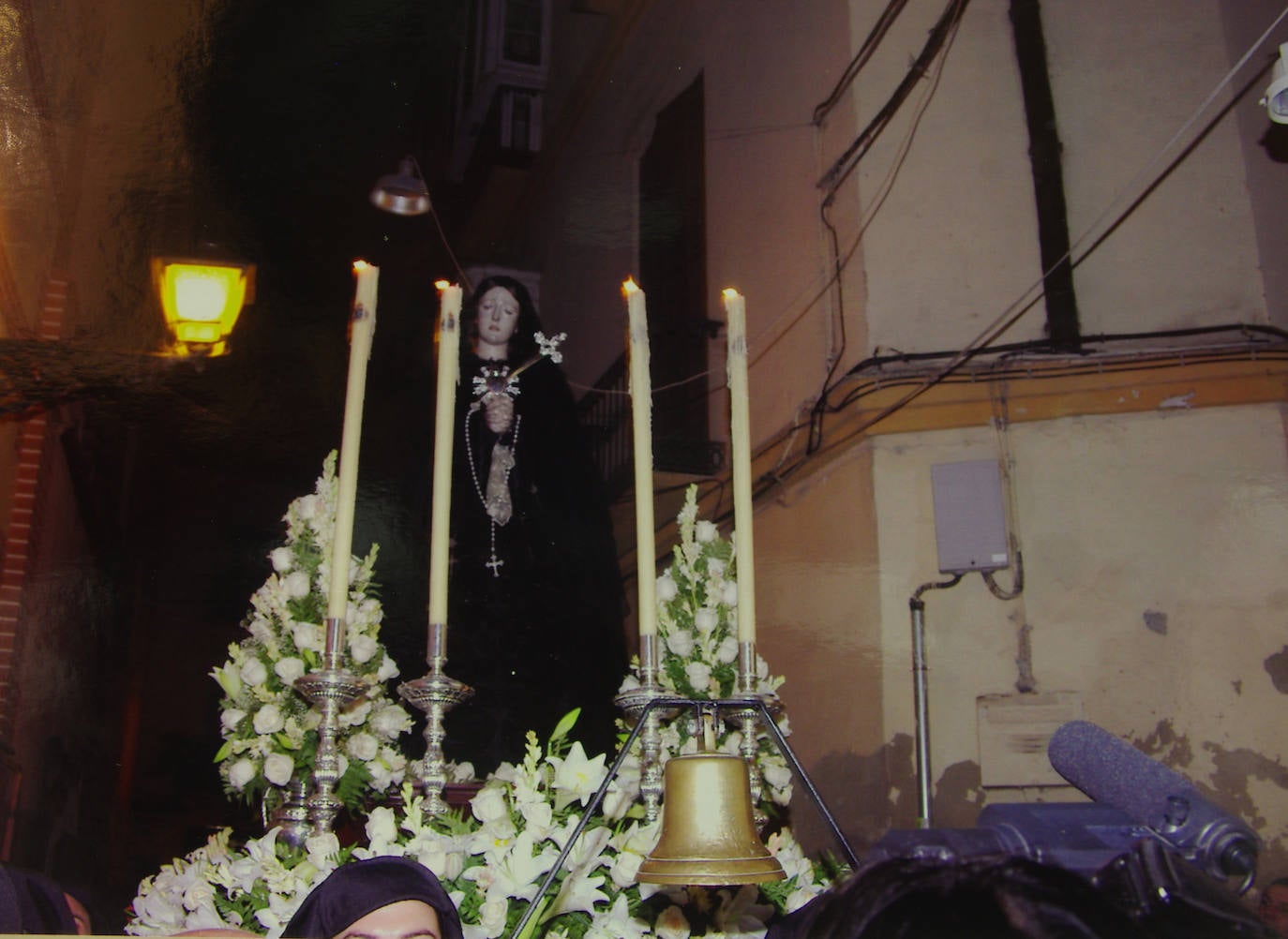 En los días previos a la coronación canónica, la Virgen de los Dolores fue objeto de un singular triduo itinerante que recorrió la basílica de la Esperanza y la parroquia de San Juan. La fotografía capta el momento del traslado desde esta última iglesia hasta la Catedral. La Virgen lució totalmente enlutada y sin corona ni ráfaga sobre sus sienes.