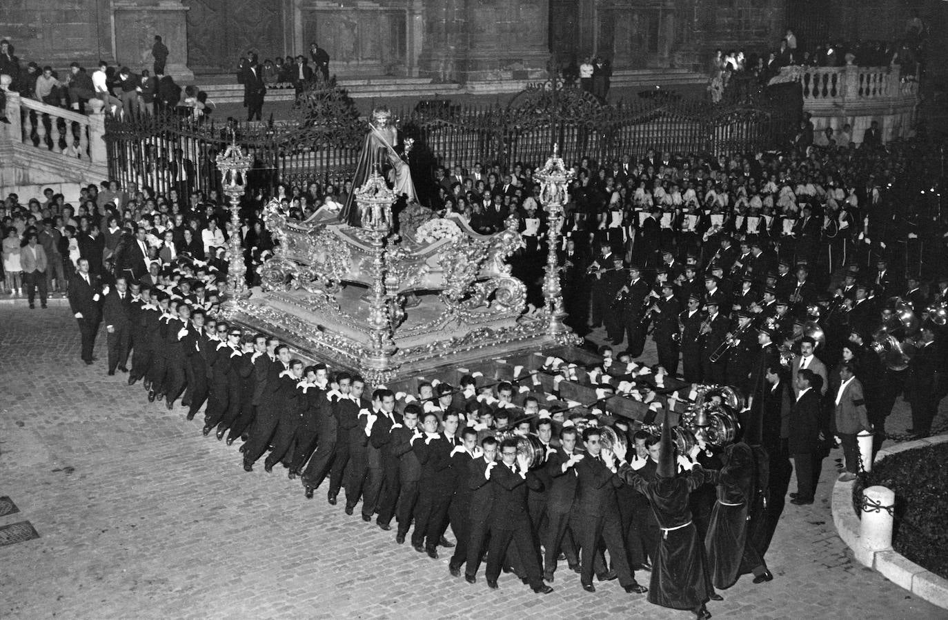 Lunes Santo de 1960. A las doce de la noche llegaba la Cofradía de los Estudiantes a la plaza del Obispo para hacer estación ante el Palacio Episcopal. Presenció el acto el obispo coadjutor, Emilio Benavent, quien pronunció unas palabras alusivas al momento y la fecha que se conmemoraba. Concluido el ritual, se encendieron las bengalas y la banda de música entonó el Himno Nacional.