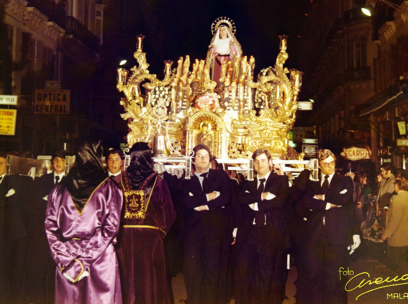 Martes Santo de 1976. La Dolorosa de Gracia enfila la calle Larios. La imagen lució una saya de color lila, donada por sus camareras. Por aquel entonces ya se había incorporado la juventud para portar los tronos de la hermandad.