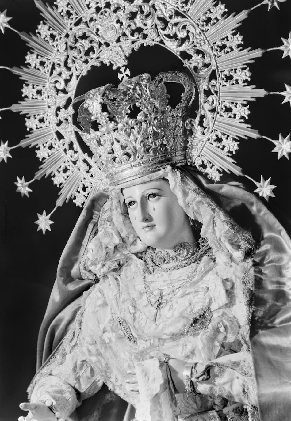 La Virgen del Rosario en sus Misterios Dolorosos ha tenido varias intervenciones desde que llegó a la Cofradía de la Sentencia para adecuar su primitiva iconografía gloriosa a la de una Dolorosa. En esta singular fotografía se observa tras una de sus primeras adaptaciones. Le colocaron lágrimas en las mejillas. Según los gustos estéticos de la época, aparece con el rostro muy enmarcado por la mantilla del tocado, y el cuello tapado igualmente por un encaje.