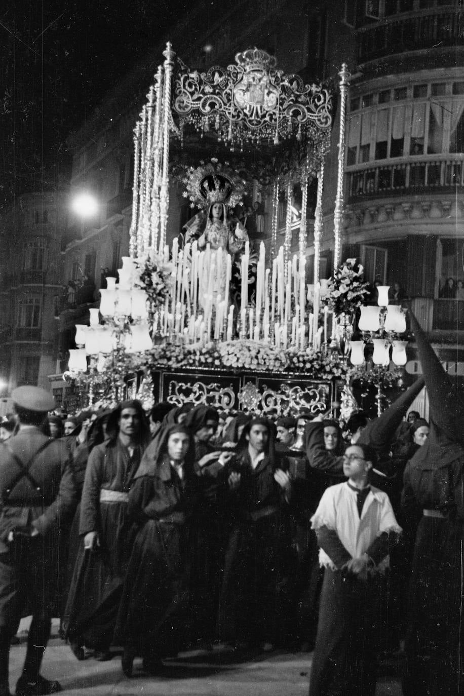 Década de los 40 del siglo XX. La Virgen de la Paloma discurre por la emblemática calle Larios. La Dolorosa apenas llevaba unos años procesionando, pues la talla bendecida en 1926, bajo la misma advocación, había desaparecido en 1936 con el estallido de la guerra civil. Como ocurriera en la anterior efigie, a la obra de José Navas-Parejo Pérez se le añadió una paloma blanca disecada en su mano izquierda. Pero el conjunto no solo contaba con esta referencia a la advocación, ya que la Virgen, por entonces, lucía un manto bordado por las Adoratrices en 1919 que contenía el escudo de Alfonso XIII en su centro y varias palomas revoloteando a su alrededor. Esta pieza artística es hoy exhibida cada Viernes Santo por la Virgen de los Dolores de la Hermandad del Santo Entierro de Almería, si bien con anterioridad lo sacó Nuestra Señora del Mayor Dolor de Melilla, donde se restauró y se pasó a un nuevo terciopelo.