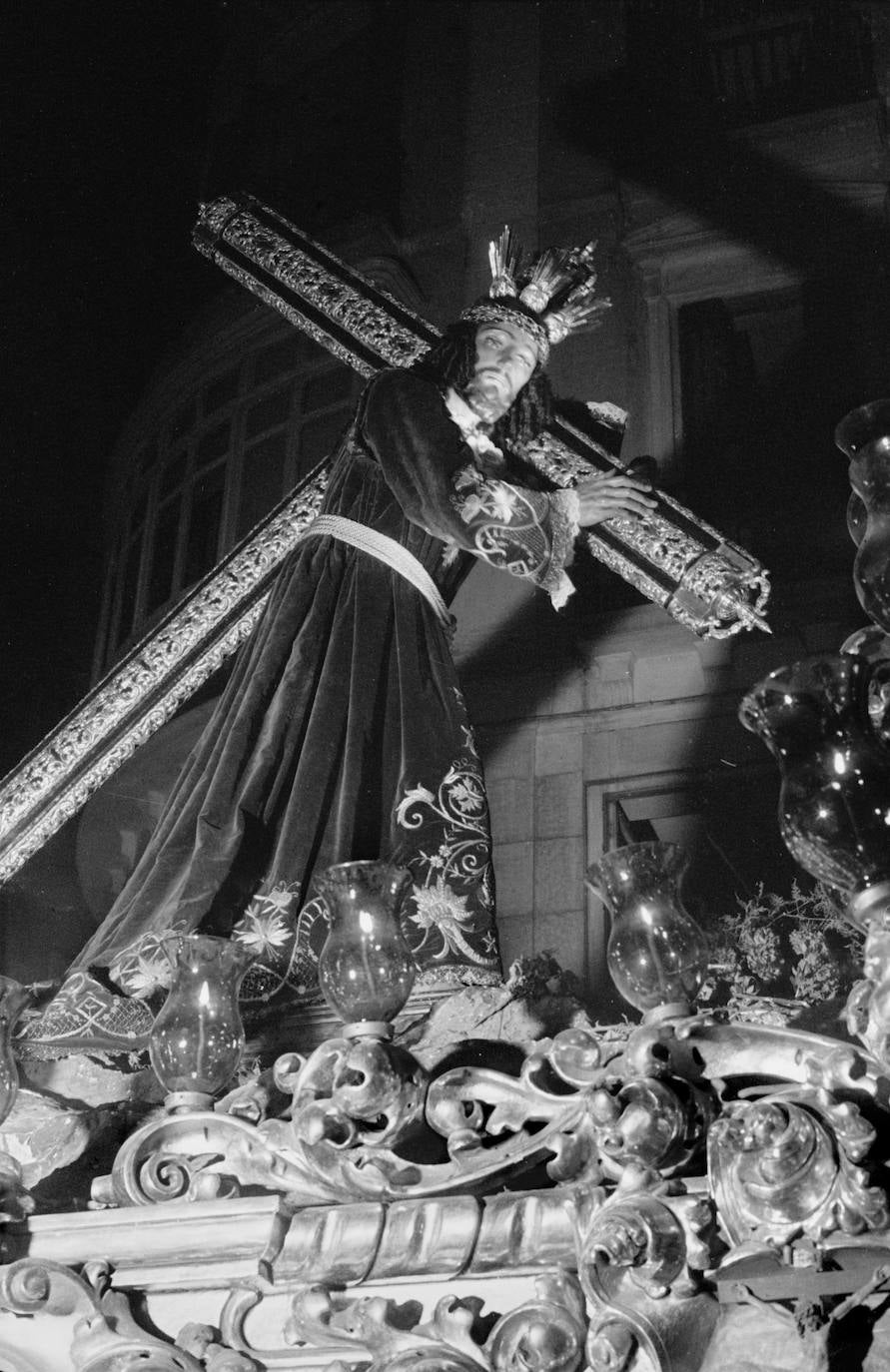 La actual cruz de madera con decoración de orfebrería de plata que luce la imagen de Jesús El Rico fue donada por la productora de la película 'Amanecer en Puerta Oscura', del año 1957, una obra de José María Forqué en la que el Cristo protagoniza una recreación del acto de liberación del preso. La orfebrería fue ejecutada en los talleres Herrera de Córdoba y la plata fue obtenida mediante una colección de monedas que consiguió la productora cinematográfica. La madera, caoba, se obtuvo del pasamanos de una escalera de la fábrica de cartón del que entonces era hermano mayor de la hermandad, Ramón Porras de Silva. La carpintería corrió a cargo de Antonio Moya, que era policía armada y hermano de la cofradía.