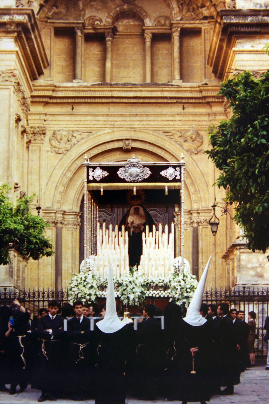 Hasta el año 1988 no se abrieron las puertas de la Catedral para que las cofradías que no solían hacer estación de penitencia en su interior pudieran recorrer sus naves. El trono de la Virgen de las Angustias aparece detenido en el patio de los Naranjos, con la puerta del primer templo de la diócesis cerrada a sus espaldas. Este año la Virgen estrenó una nueva corona obra de los talleres de orfebrería Mallol, según diseño de Antonio Dubé de Luque.