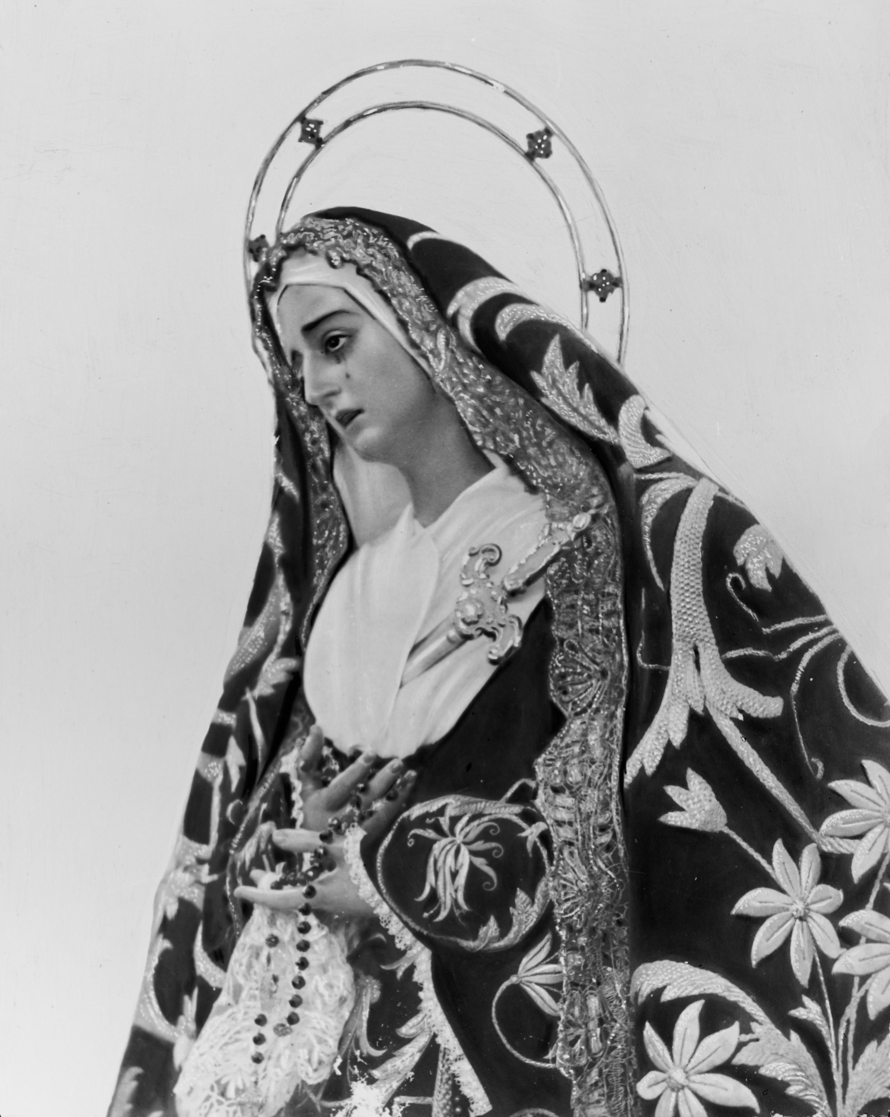 Si existe una imagen mariana en la Semana Santa de Málaga que se distingue por su estilo personal e inconfundible, esa es la Virgen de la Soledad de la Hermandad del Santo Sepulcro. La talla es obra de José Merino Román, un malagueño que emigró a Sevilla y estableció su taller en el número 66 de la calle Relator, en el barrio de la Macarena. La pieza en cuestión la realizó en 1934. En principio, su destino iba a ser la hermandad sevillana de la Hiniesta, ya que los titulares de esta corporación fueron pasto de las llamas durante un incendio intencionado acaecido en su sede de San Julián. En cambio, la efigie fue desechada a favor de otra figura, de Antonio Castillo Lastrucci, y regresó al obrador de Merino Román. Pese al revés, el imaginero intentó colocar la Dolorosa en la Hermandad de los Gitanos, y en 1935, el jueves 4 de abril, fue bendecida bajo la advocación de las Angustias, toda vez que en esta fraternidad existieron pretensiones por reemplazar la obra de José Montes de Oca por otra de nueva ejecución. Incluso, la Virgen de Merino llegó a procesionar bajo palio en la 'Madrugada' sevillana. Sin embargo, el cambio de Dolorosa no gustó a los hermanos de los Gitanos, de ahí que en 1936 volviera a salir la primitiva titular que, posteriormente, fue destruida el 18 de julio de ese mismo año al ser incendiado el templo de San Román por los radicales. Entre tanto, la Virgen del escultor malagueño volvió a su taller hasta que la Hermandad del Santo Sepulcro de Málaga la adquirió en propiedad y la bendijo en la primavera de 1938.