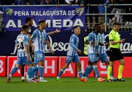 Jugadores del Málaga tras el árbitro De la Fuente Ramos para reclamar una de sus decisiones en el partido contra el Levante en La Rosaleda.