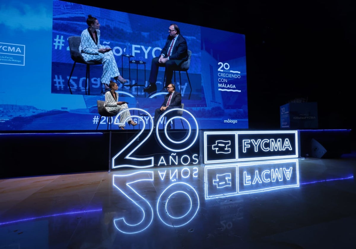 El consejero de turismo, Arturo Bernal, conversa con la moderadora del acto del 20 aniversario del Palacio de Ferias.