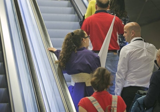 Una joven nazarena en las escaleras mecánicas de una estación del metro.