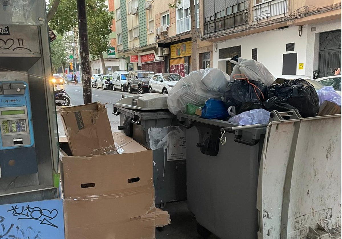 Contenedores llenos cerca de una cabina abandonada.