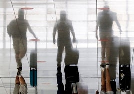 Turistas avanzan por una pasarela del aeropuerto para iniciar su viaje.