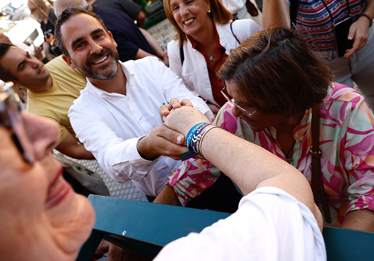 Dani Pérez, con otros candidatos socialistas, en el mercado de Huelin, poniendo pulseritas de su campaña electoral.