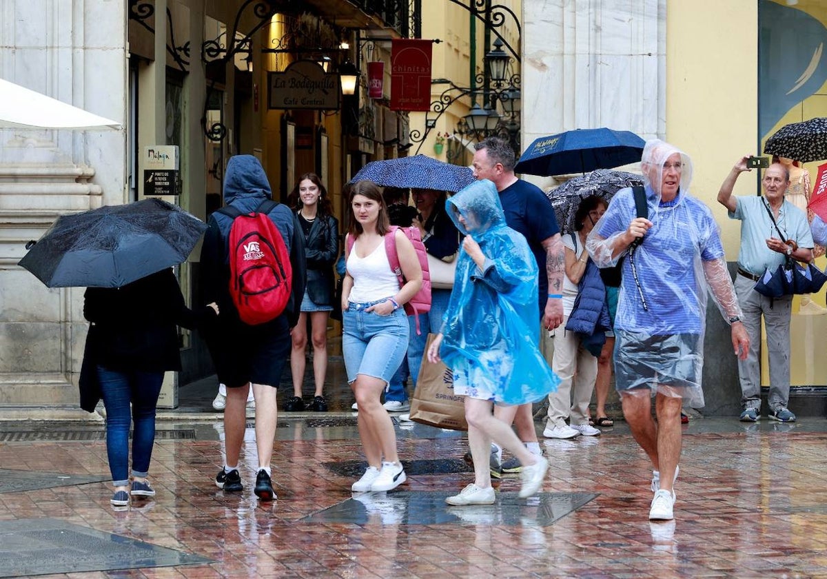 Turistas con chubasqueros y paraguas, ayer en el Centro de Málaga.