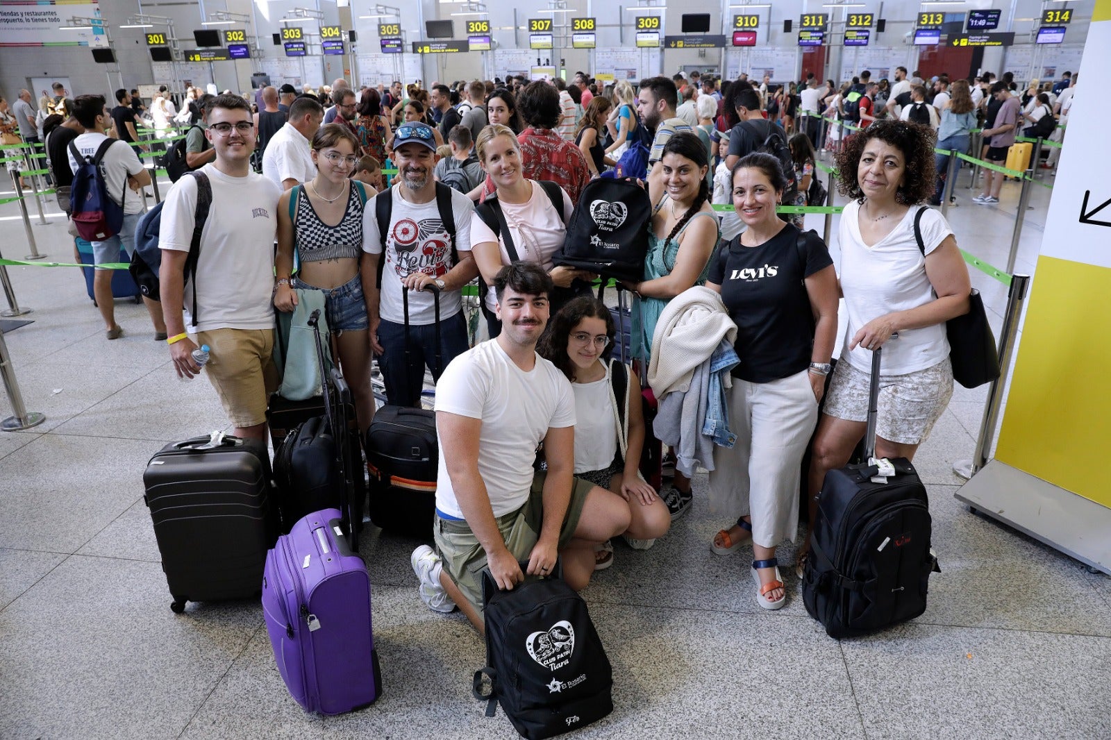 Agachados, Fernando y Leire, del club de patinaje artístico Tiara de El Rosario (Tenerife). Con compañeros del club, familiares y entrenadora regresan a Tenerife tras participar en el campeonato celebrado en Fuengirola.