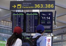 Turistas buscan su vuelo en unos paneles informativos del aeropuerto de Málaga.