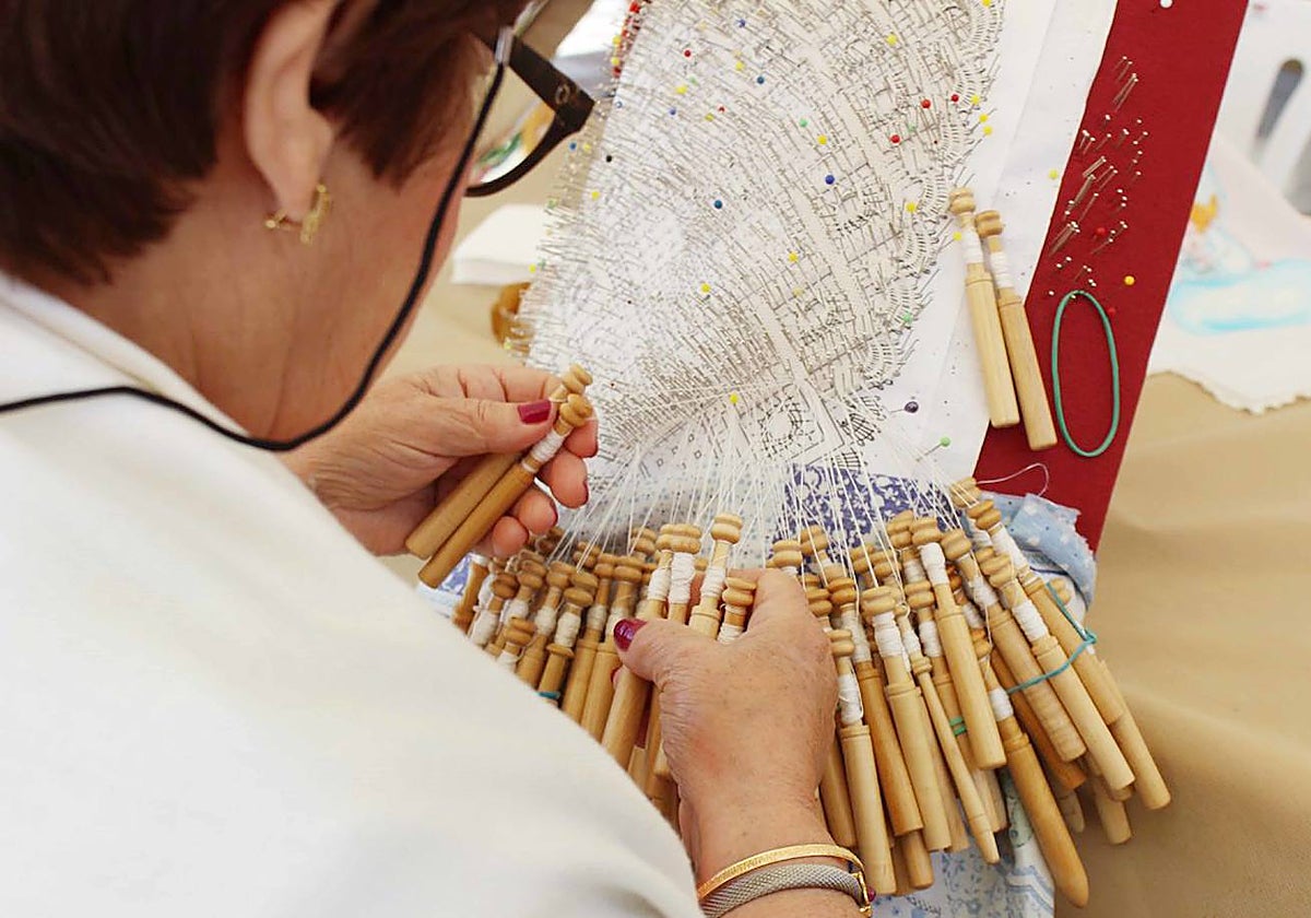 Una mujer haciendo encaje de bolillos.