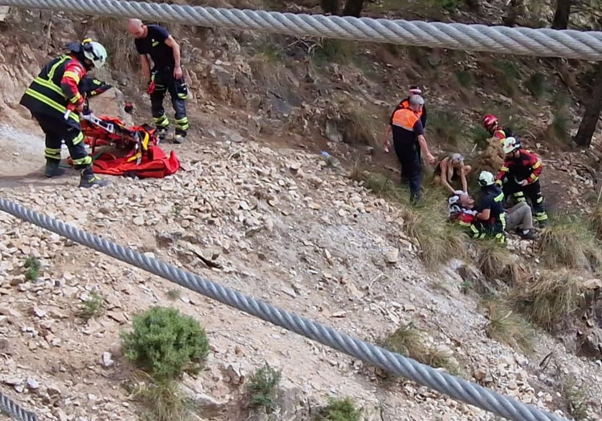 Efectivos de Bomberos y de Protección Civil asisten al herido, este domingo en Canillas de Aceituno.