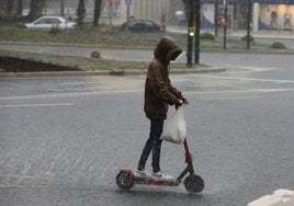 Un joven circula con un patinete bajo la lluvia en un episodio reciente.