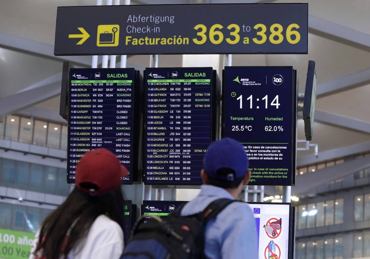 Viajeros buscan su vuelo en el panel informativo del aeropuerto de Málaga.