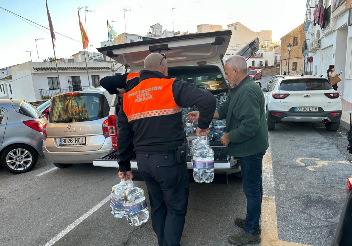 Reparto de garrafas de agua entre los vecinos de Maro, este viernes, por parte de voluntarios de Protección Civil.