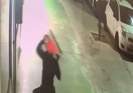 El supuesto autor de los robos, en el momento en que reventaba un escaparate con ayuda de una arqueta.