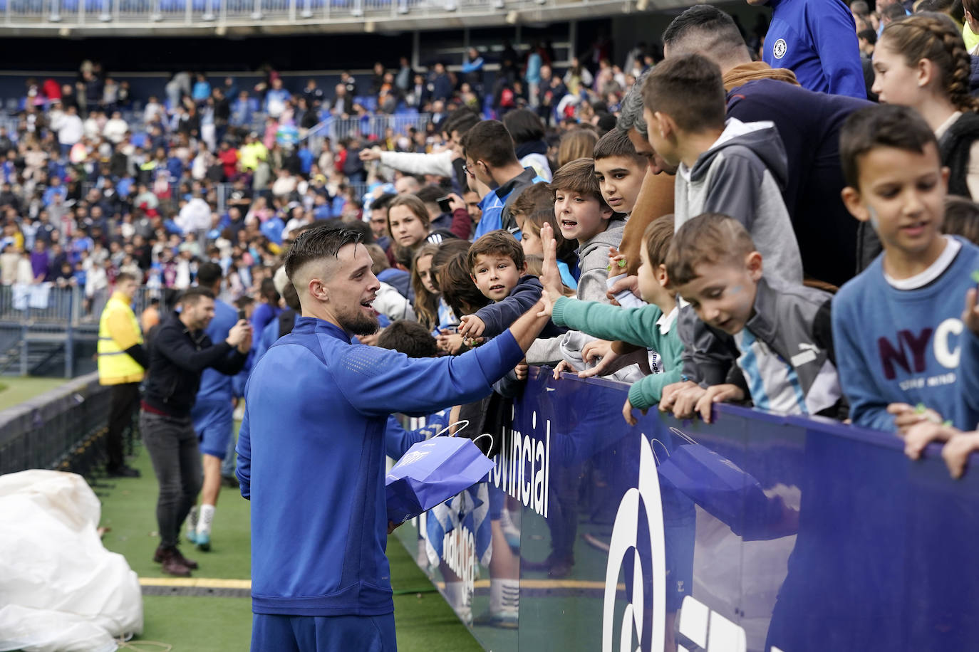 Miles de seguidores, entre ellos muchos niños, acuden en masa a La Rosaleda para ver una sesión de trabajo del equipo blanquiazul en la víspera del Día de Reyes. 