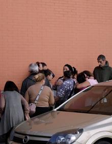 Imagen secundaria 2 - Familiares y vecinos, consternados por lo ocurrido. Abajo, a la izquierda, dos agentes custodian la entrada del edificio en el que sucedieron los hechos. 