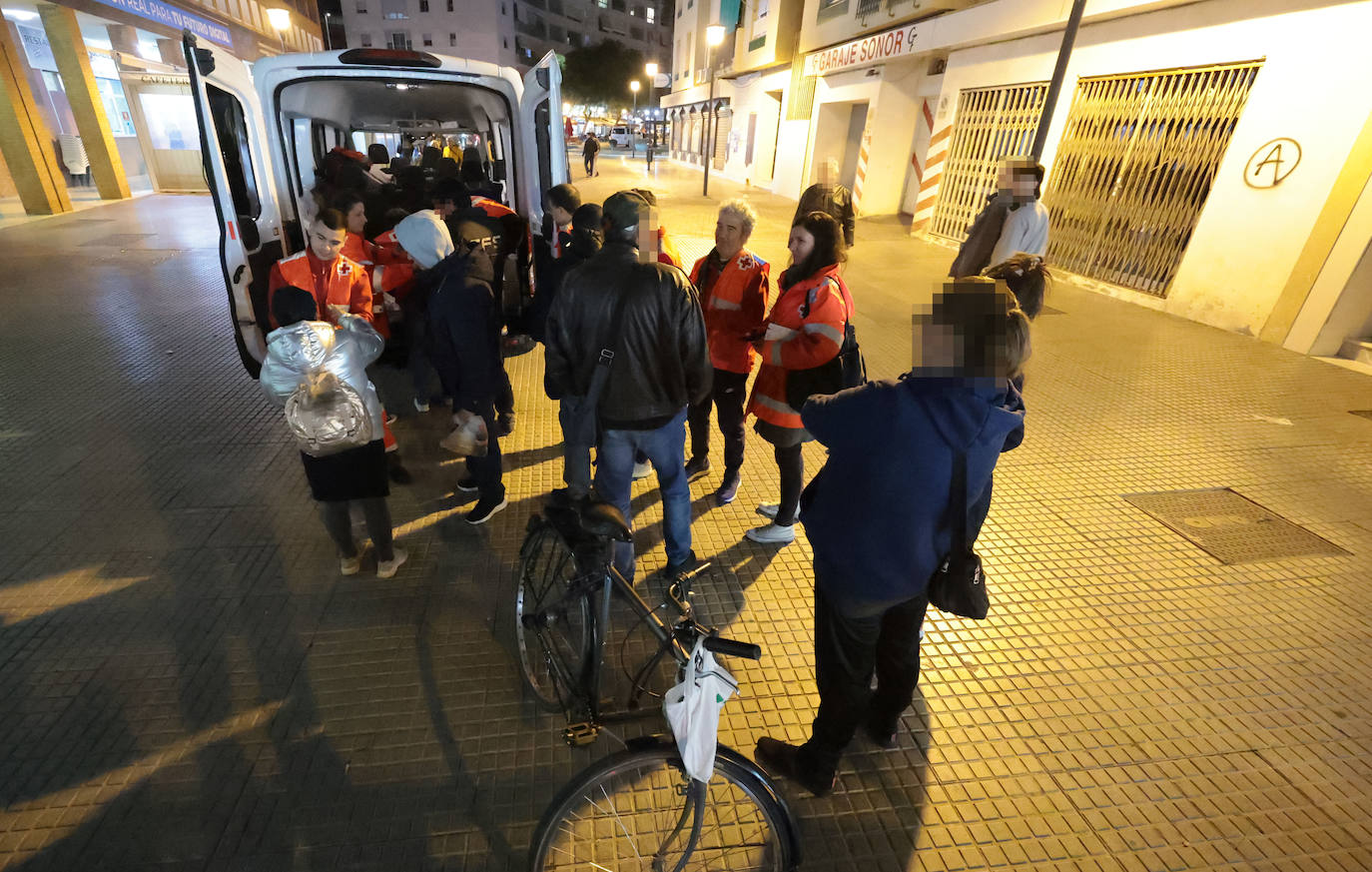 Los voluntarios realizando el reparto de mantas y comida mientras conversan con las personas sin hogar. 