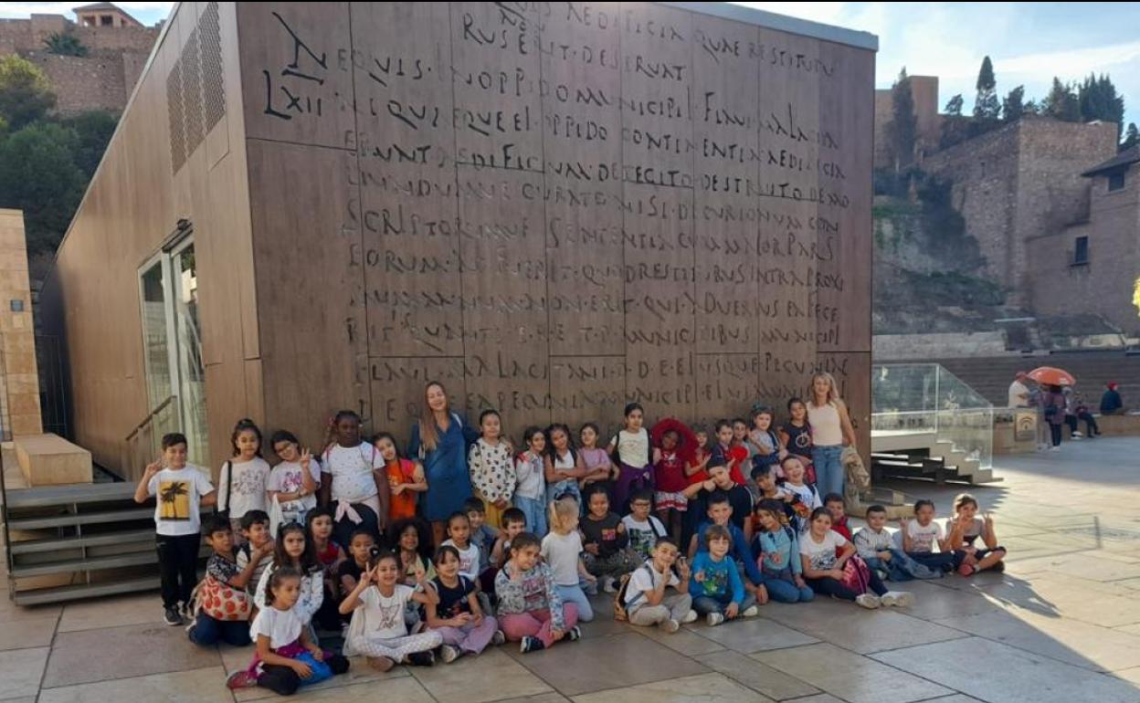 Un grupo de estudiantes y profesoras del Lex Flavia junto a la reproducción de las tablas que hay en una de las paredes del centro de visitantes del Teatro Romano. 