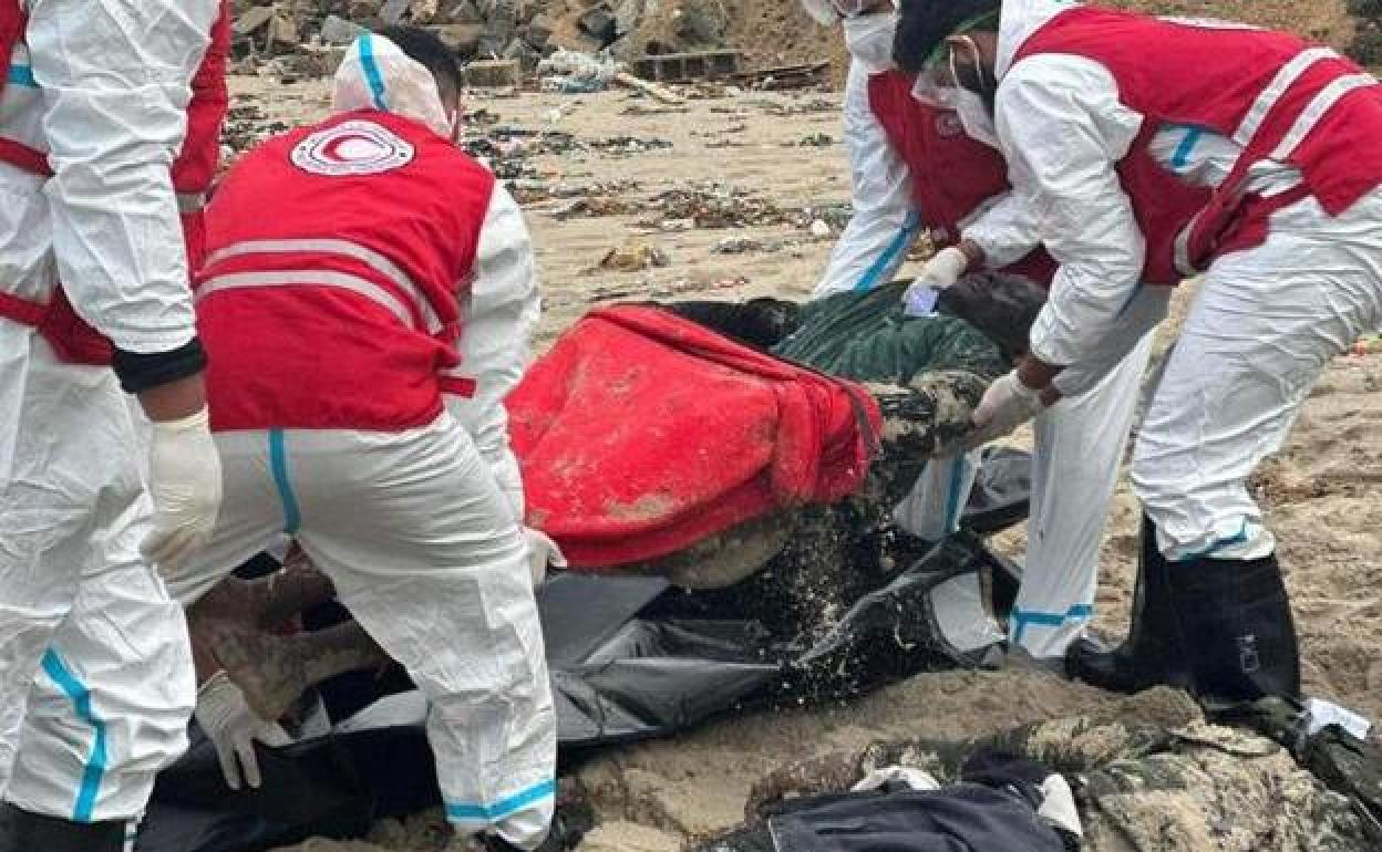 Trabajadores de la Media Luna Roja Libia introducen en una bolsa el cuerpo de uno de los migrantes fallecidos