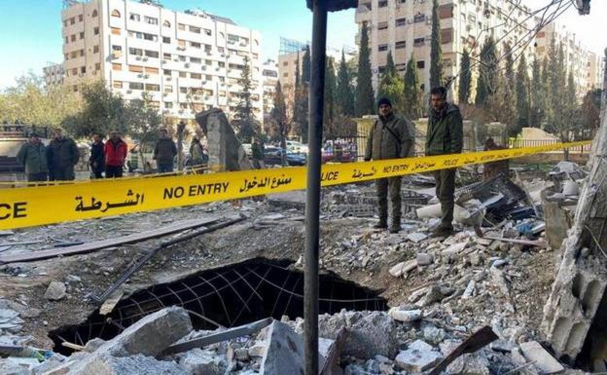 Agentes de policía observan el socavón provocado en una calle de Damasco por los bombardeos.