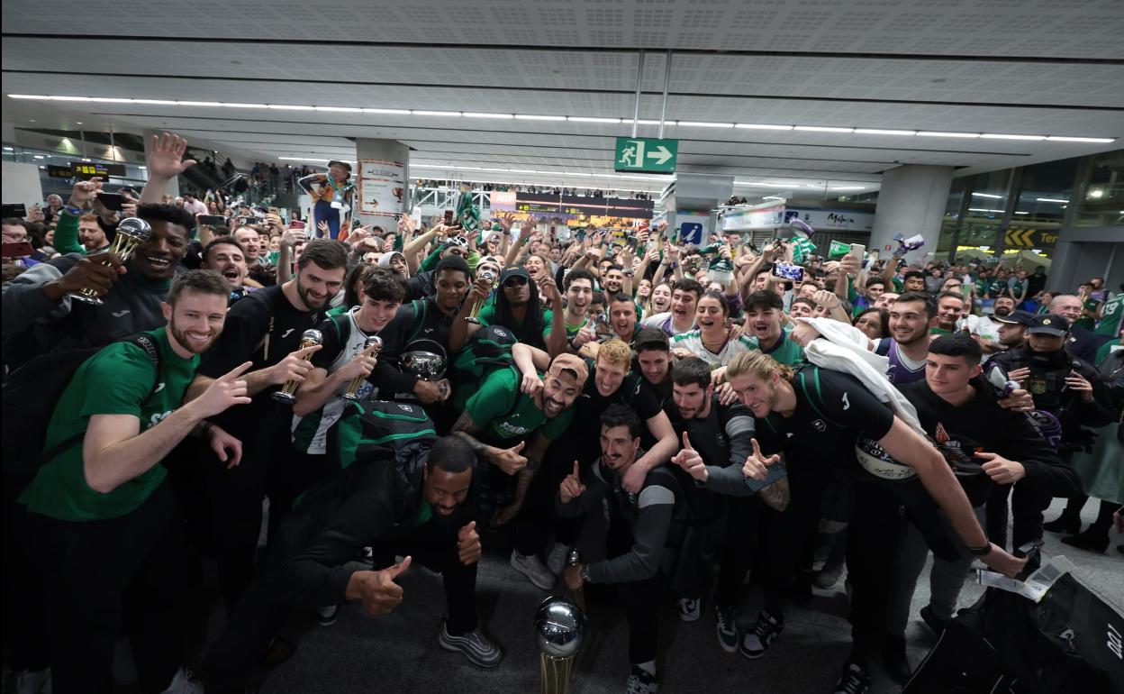 La plantilla del Unicaja posa con la Copa del Rey junto a los aficionados que le recibieron en el aeropuerto de madrugada.