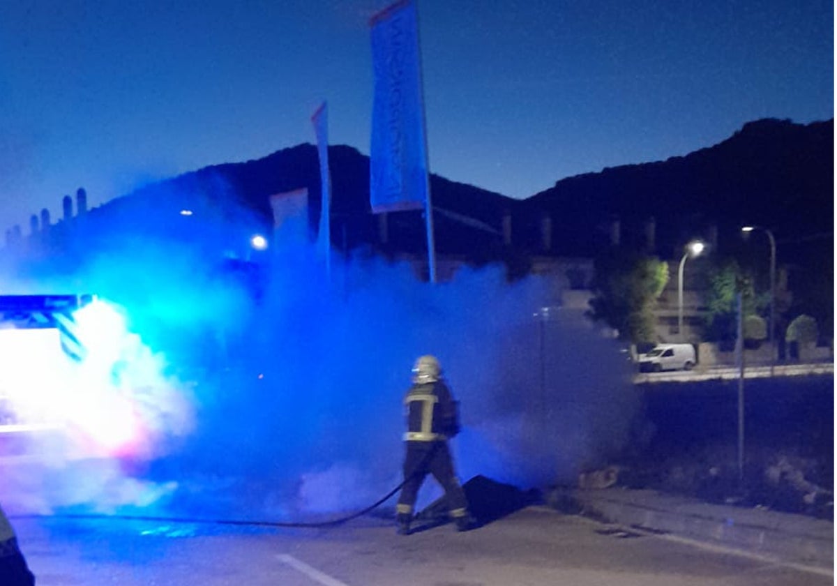 Un bombero trata de sofocar las llamas en el contenedor.