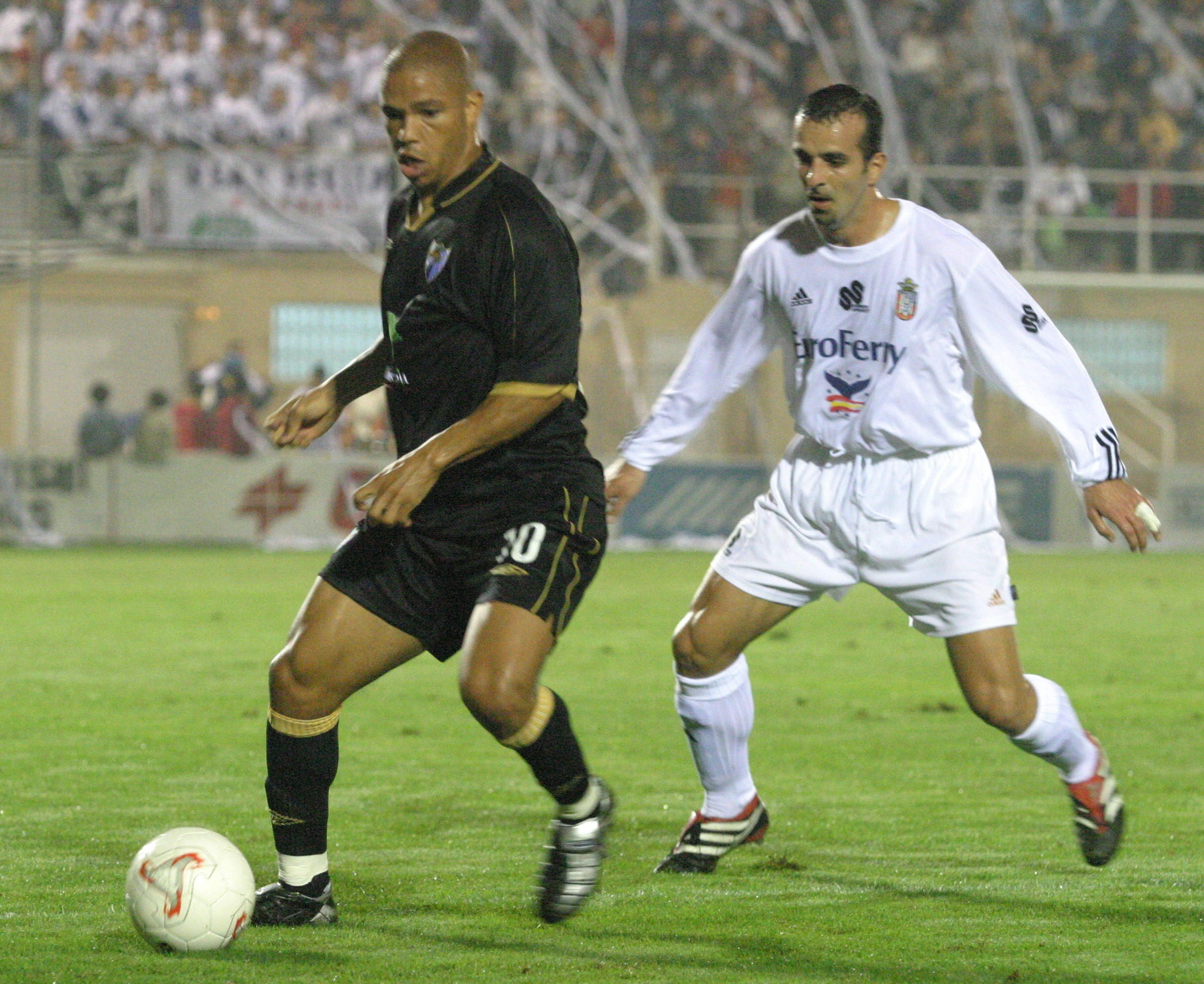 El jugador del Málaga CF, Edgar (i), intenta controlar el balón, ante la mirada de un jugador ceutí, durante el partido del Copa del Rey jugado en el año 2000 en el estadio Alfonso Murube.