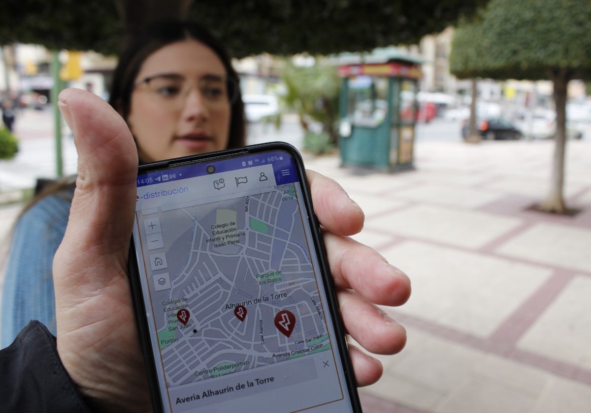 Un vecino consulta una «app» que informa sobre fallos en la red eléctrica, mientras conversa sobre el apagón en Alhaurín de la Torre.