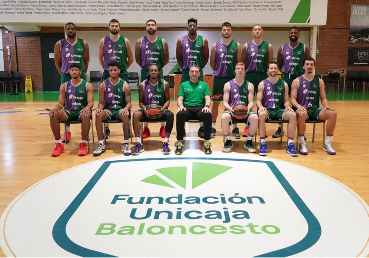 La plantilla del Unicaja posa delante del nuevo escudo del club, que también aparece en las equipaciones de juego.