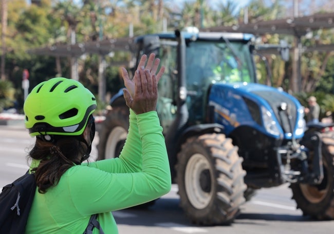 Un peatón aplaude a un agricultor que conduce su tractor, en señal de apoyo.