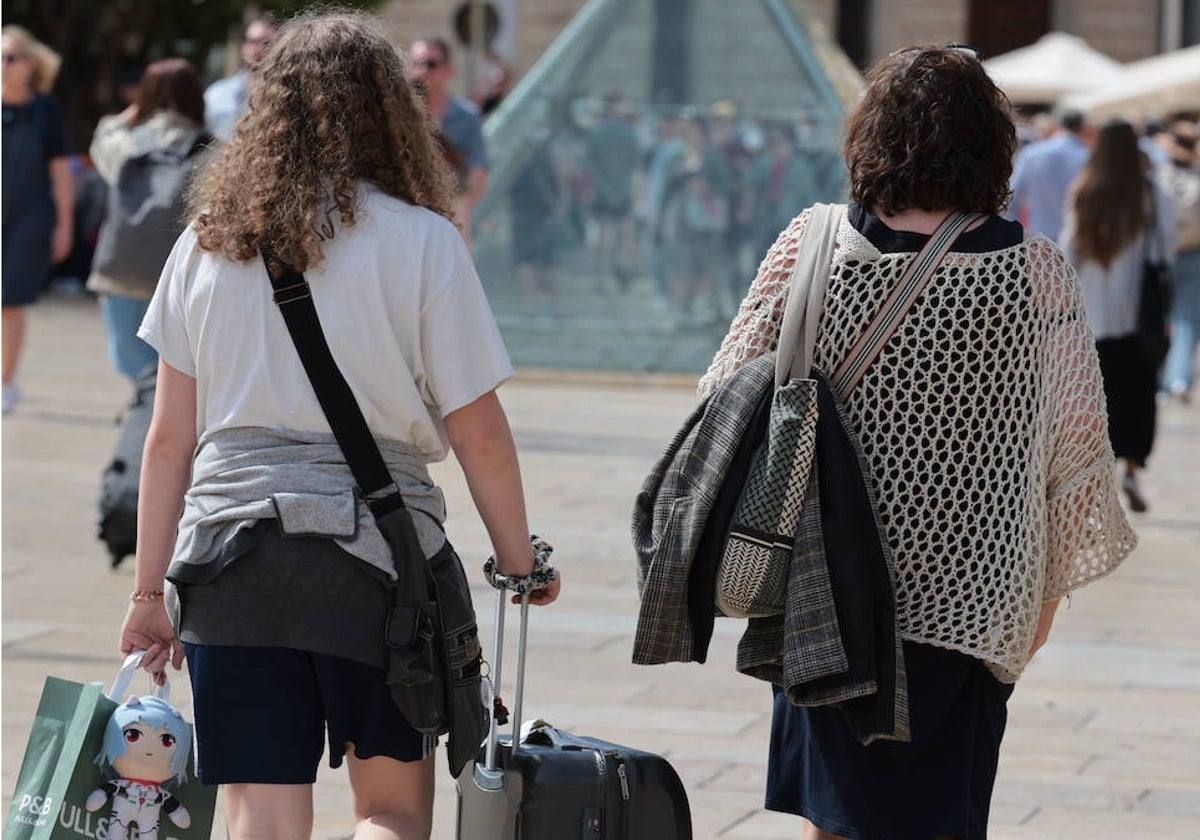 Turistas se dirigen por el Centro de Málaga a su alojamiento.